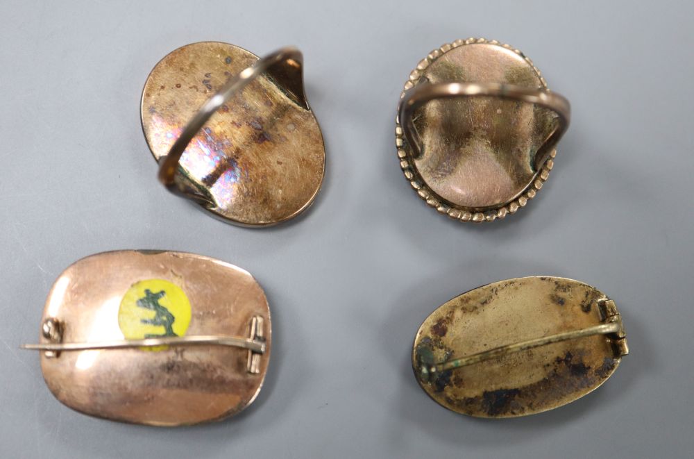 Three assorted yellow metal and glazed silhouette rings and two brooches, including sulphide dog, gross 21.2 grams.